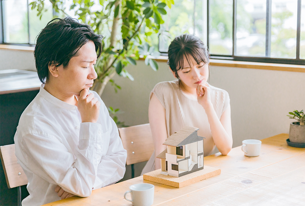 不動産の模型の前で考える男女　イメージ